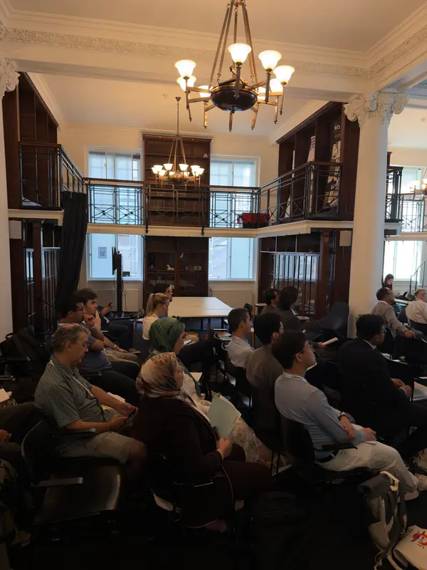 A full session hall under two chandeliers.