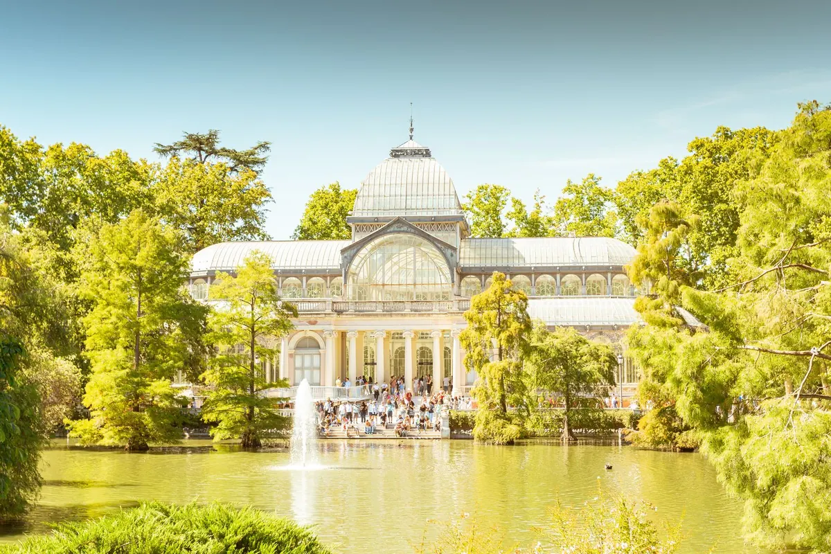 Palacio de Cristal, the glass pavilion by the pond in El Retiro park, on a sunny day